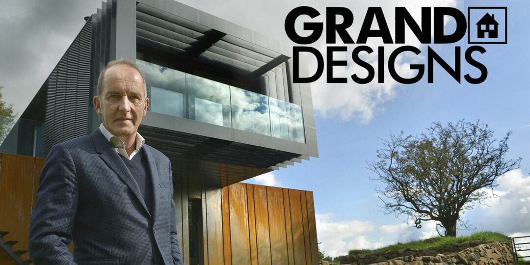 Homem parado na frente de uma casa grande da Grand Designs.