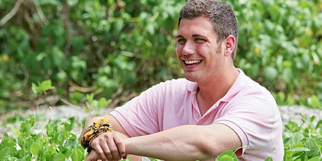 Colton Cumbie sitzt auf dem Boden und lächelt Survivor an